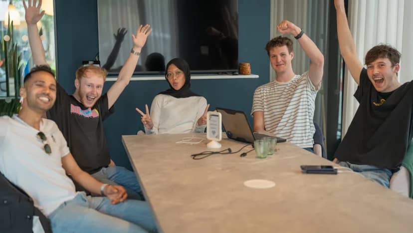 The AssumeAI team cheering around the boardroom table on their team day, June 2026